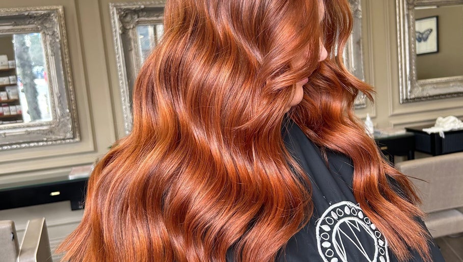 Vibrant red hair styled in waves at Eve Woods Hair, Harrogate, England, GB. Modern salon interior.