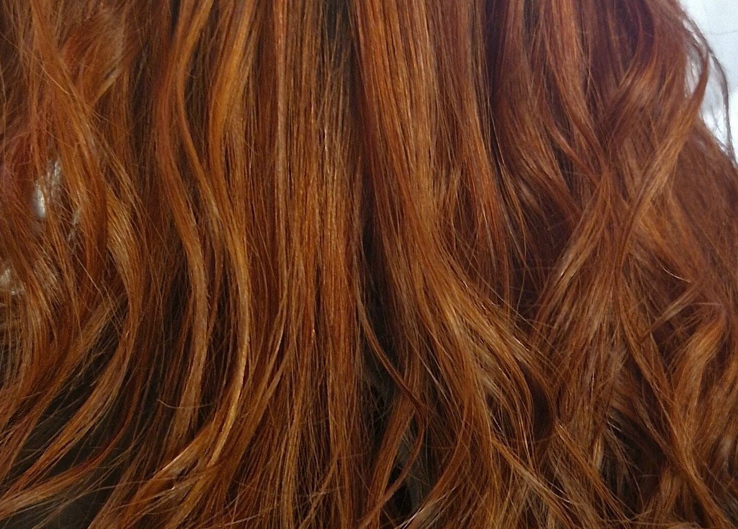 Vibrant red hair styled at BeeUnique, Northampton, England, GB, showcasing beautiful waves and shine.