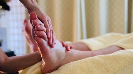 Therapist performing foot massage at Marie Johnson Holistic Therapies in Crediton, England, GB for relaxation.