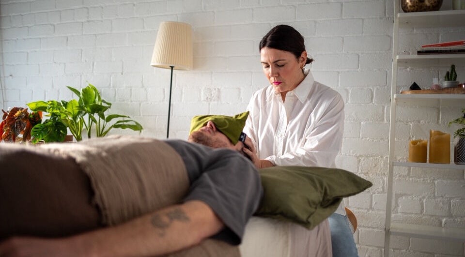 Therapist at The Tides in Leeds, GB performing a relaxing head massage in a serene, plant-filled room.