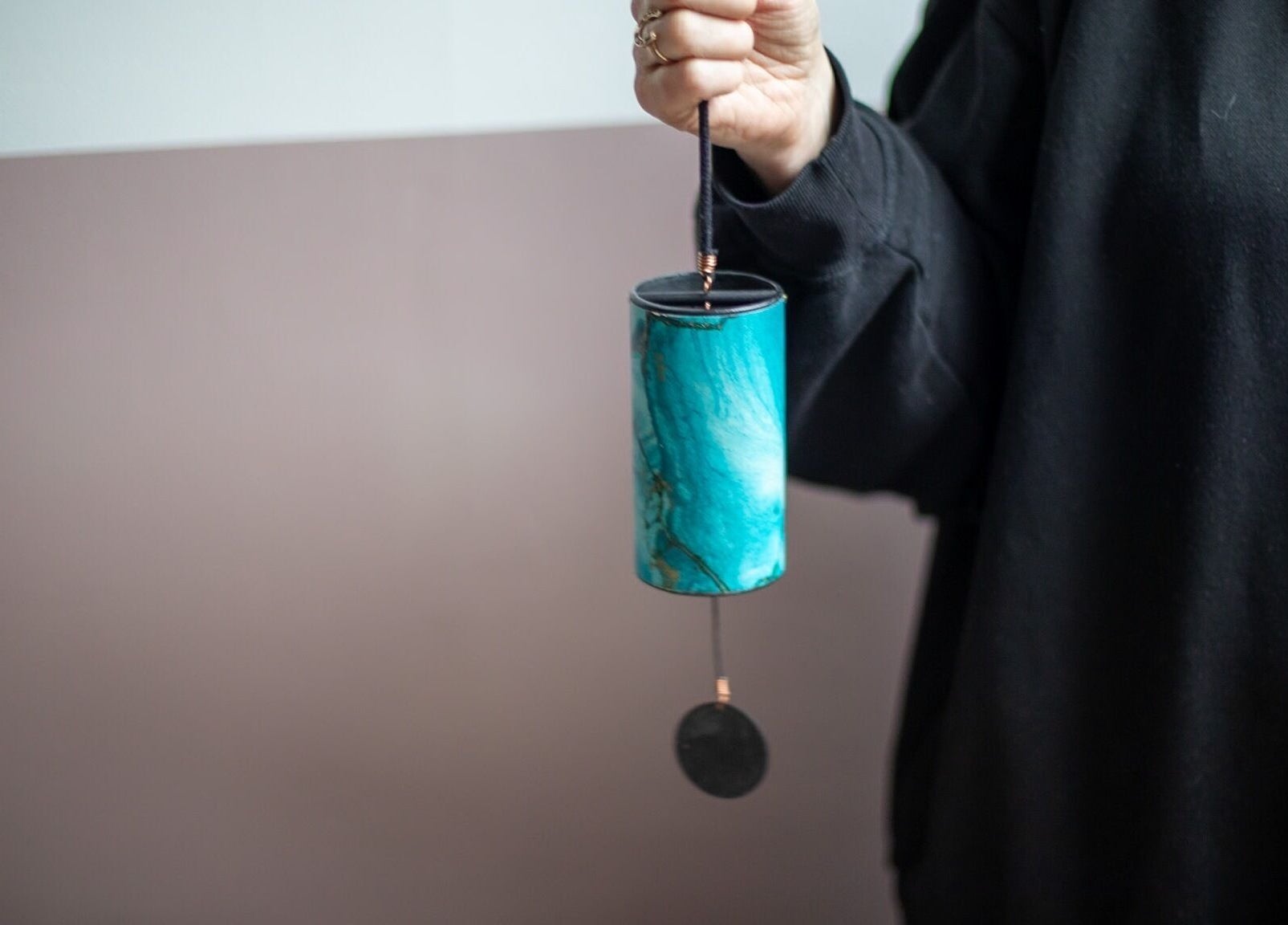 Person holding turquoise chime at The Tides, Leeds, GB, showcasing artistic craftsmanship.