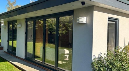 Modern garden view at Eden Beauty, Oxford, England, GB, featuring glass doors and lush greenery.