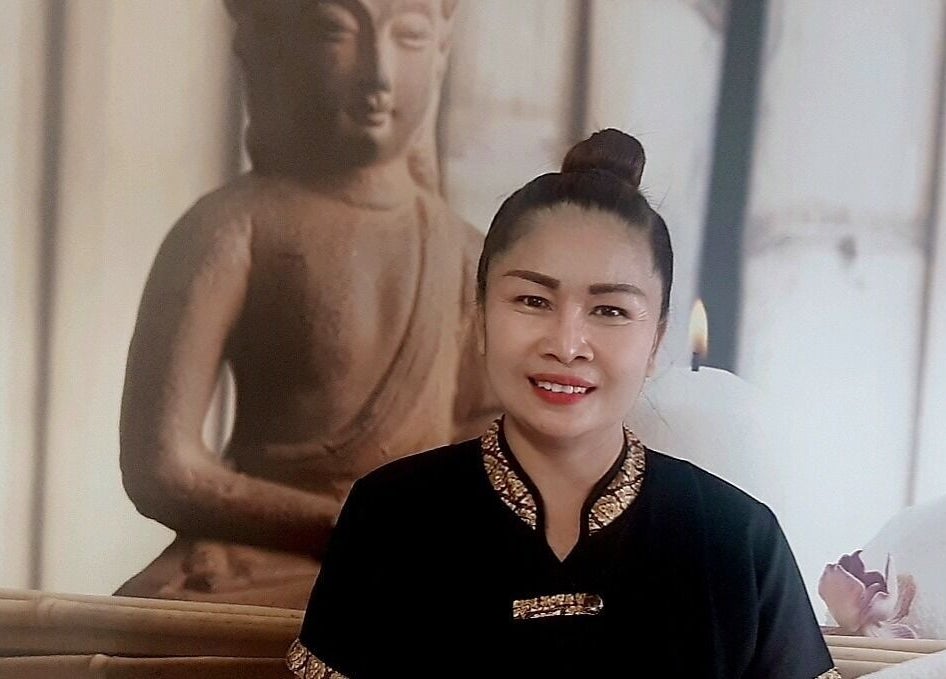 Mosolygó nő a Menta Thai Massage, Mosonmagyaróvár 9200. Jókai utca 6.-ban egy buddhista szobor előtt.