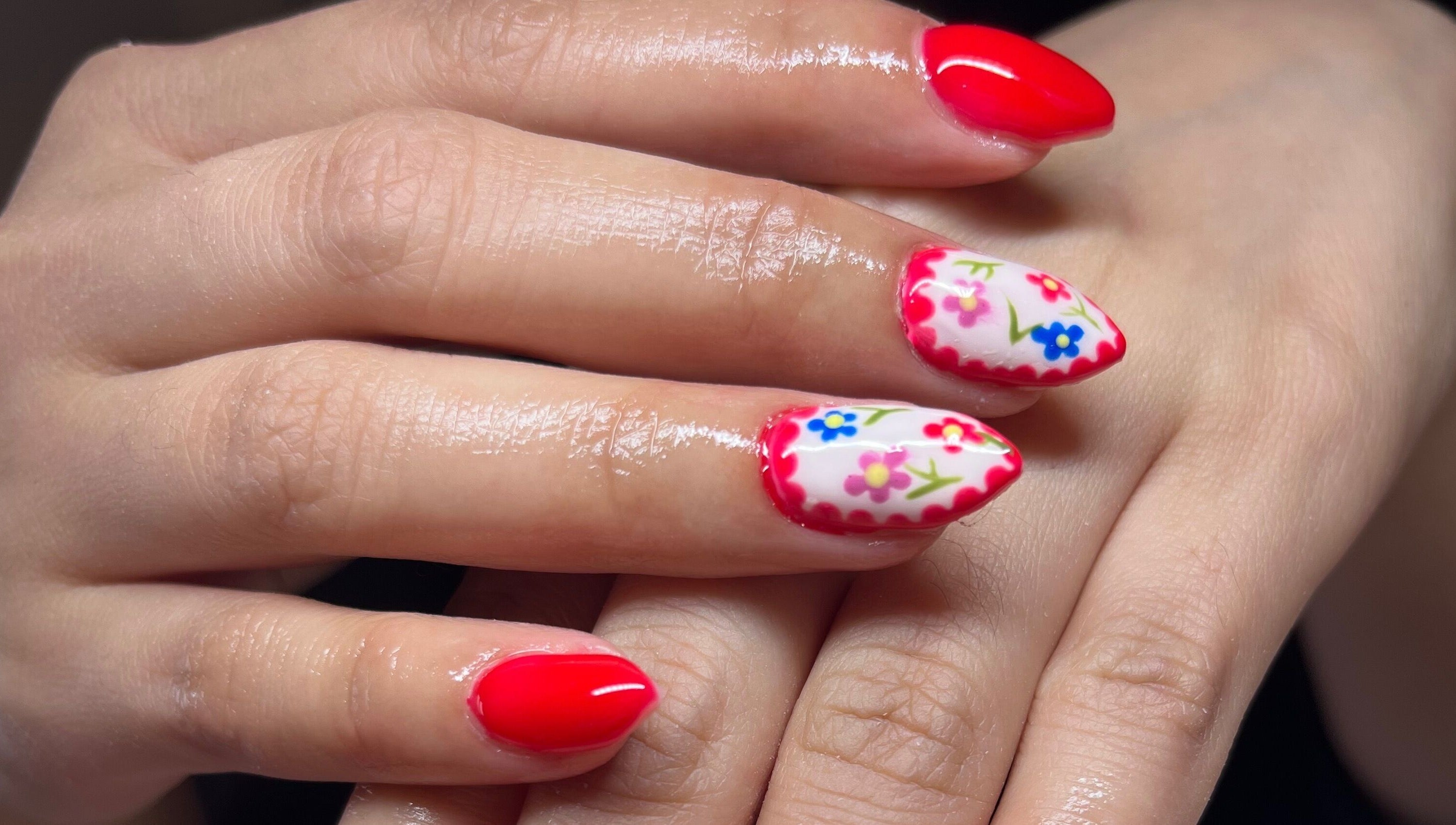 Vibrant floral nail design at Clos Beauty, Peterborough, England, GB. Red and white nails with floral accents.