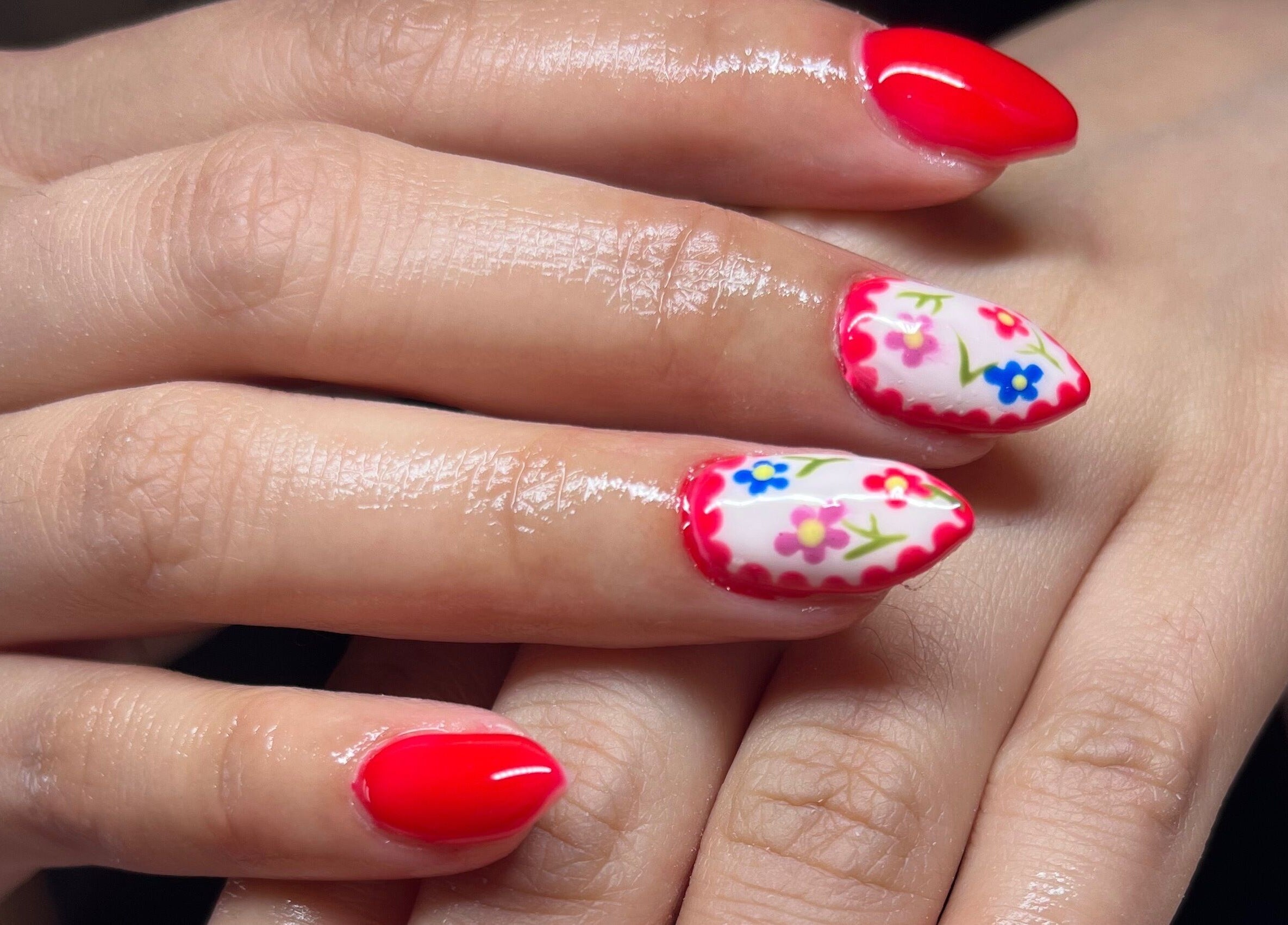 Vibrant floral nail design at Clos Beauty, Peterborough, England, GB. Red and white nails with floral accents.