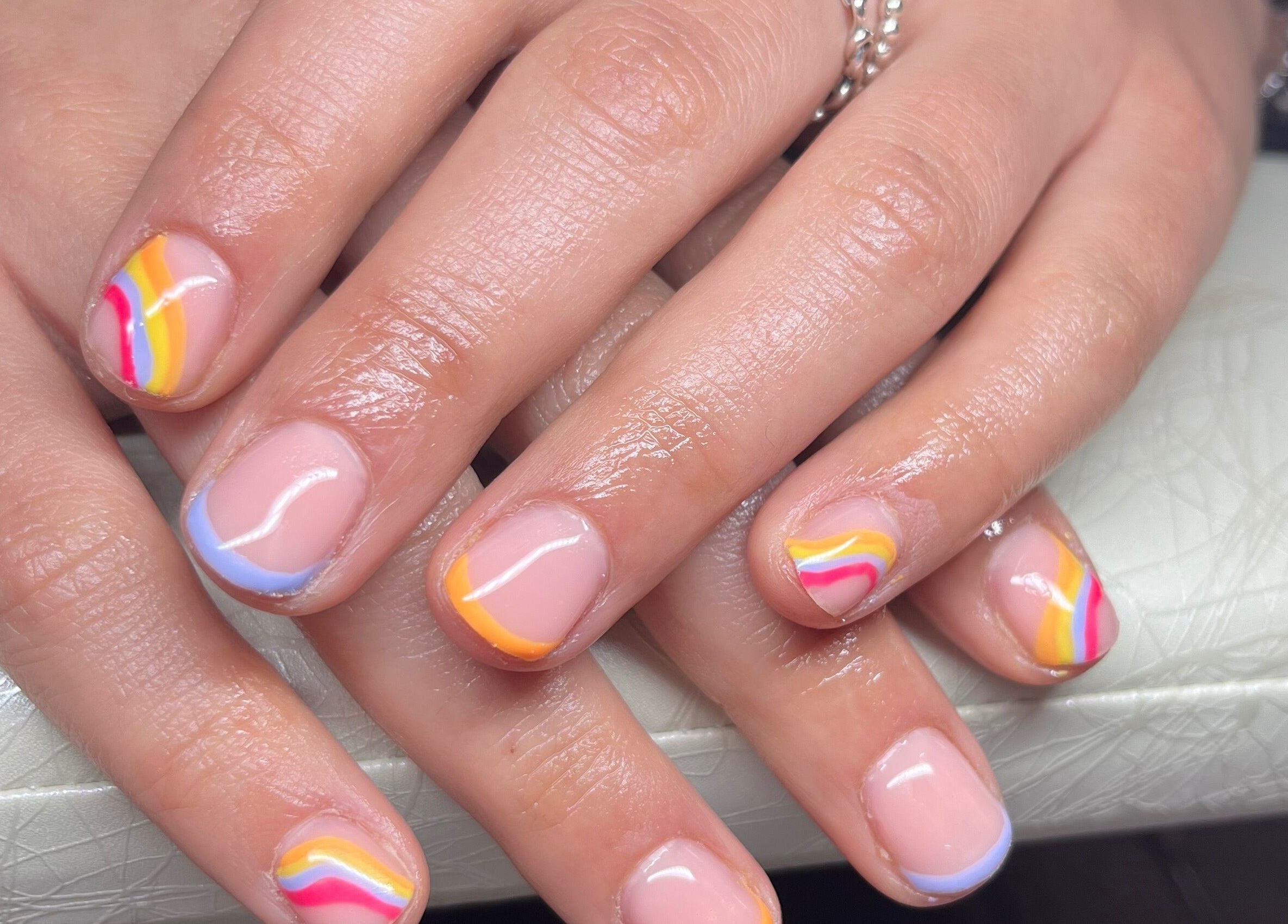 Stylish rainbow nail art at Clos Beauty in Peterborough, England, GB on a white cushion.
