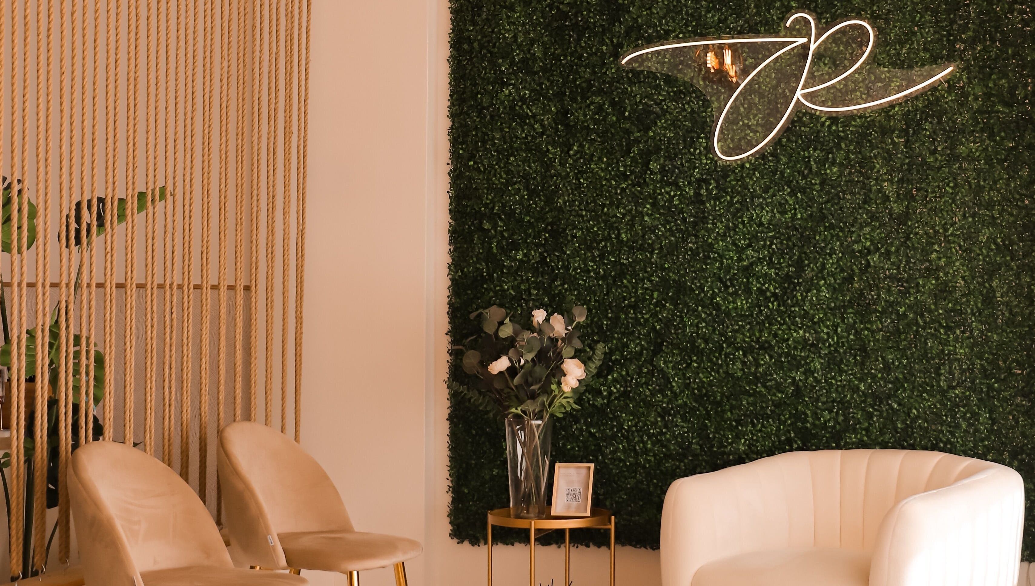 Interior acolhedor da JORA Aesthetics | Clinic & Academy em Braga, Braga, PT com parede verde e poltronas elegantes.