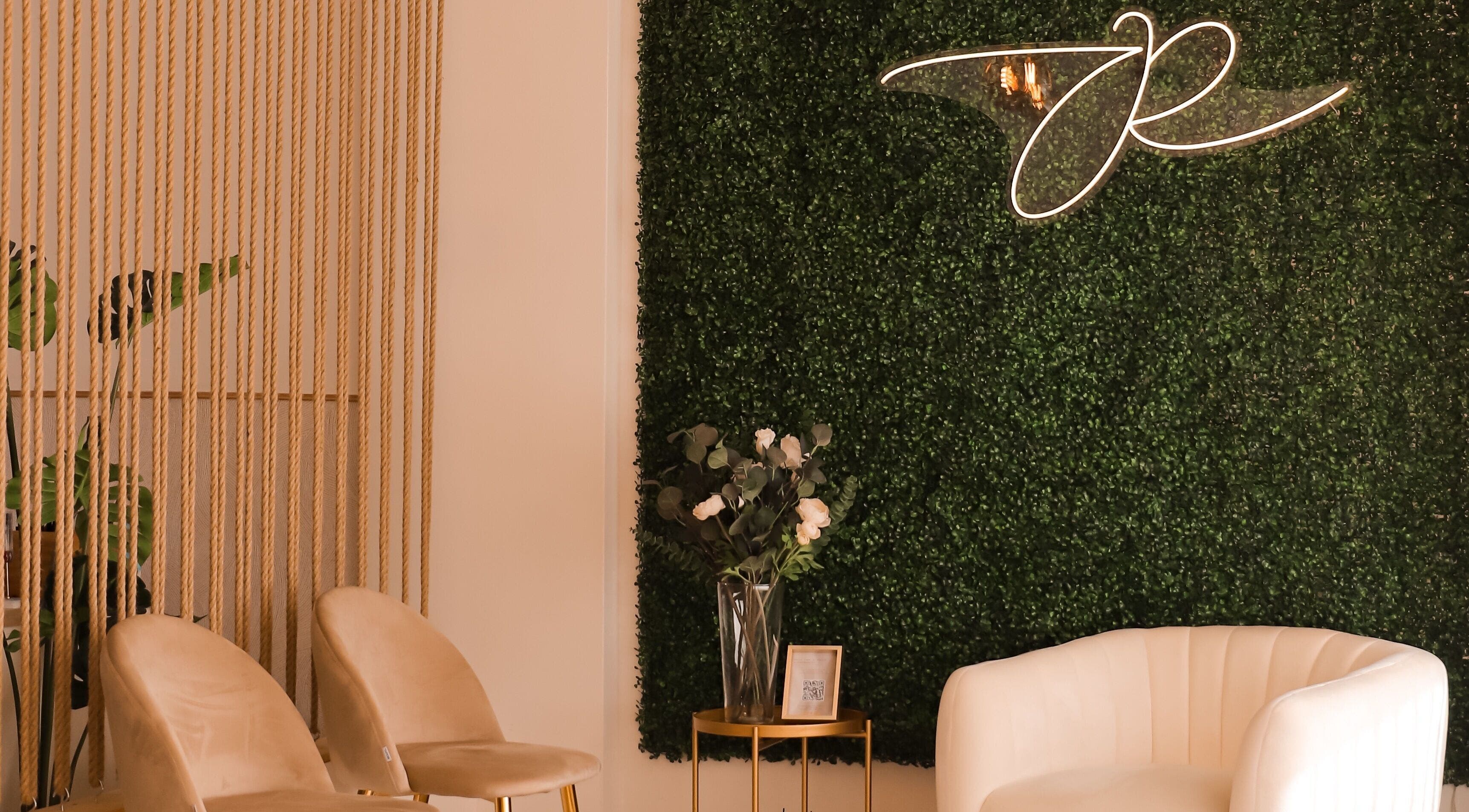 Interior acolhedor da JORA Aesthetics | Clinic & Academy em Braga, Braga, PT com parede verde e poltronas elegantes.