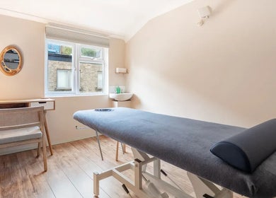 Calm treatment room at Alice Pearl Somatics, London, England, GB with massage table and desk.