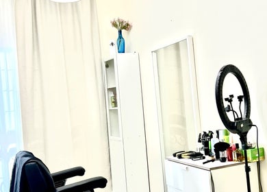 Calm salon interior at Just A Smile Salon, Doha, with styling chair, ring light, and products on a white cabinet.
