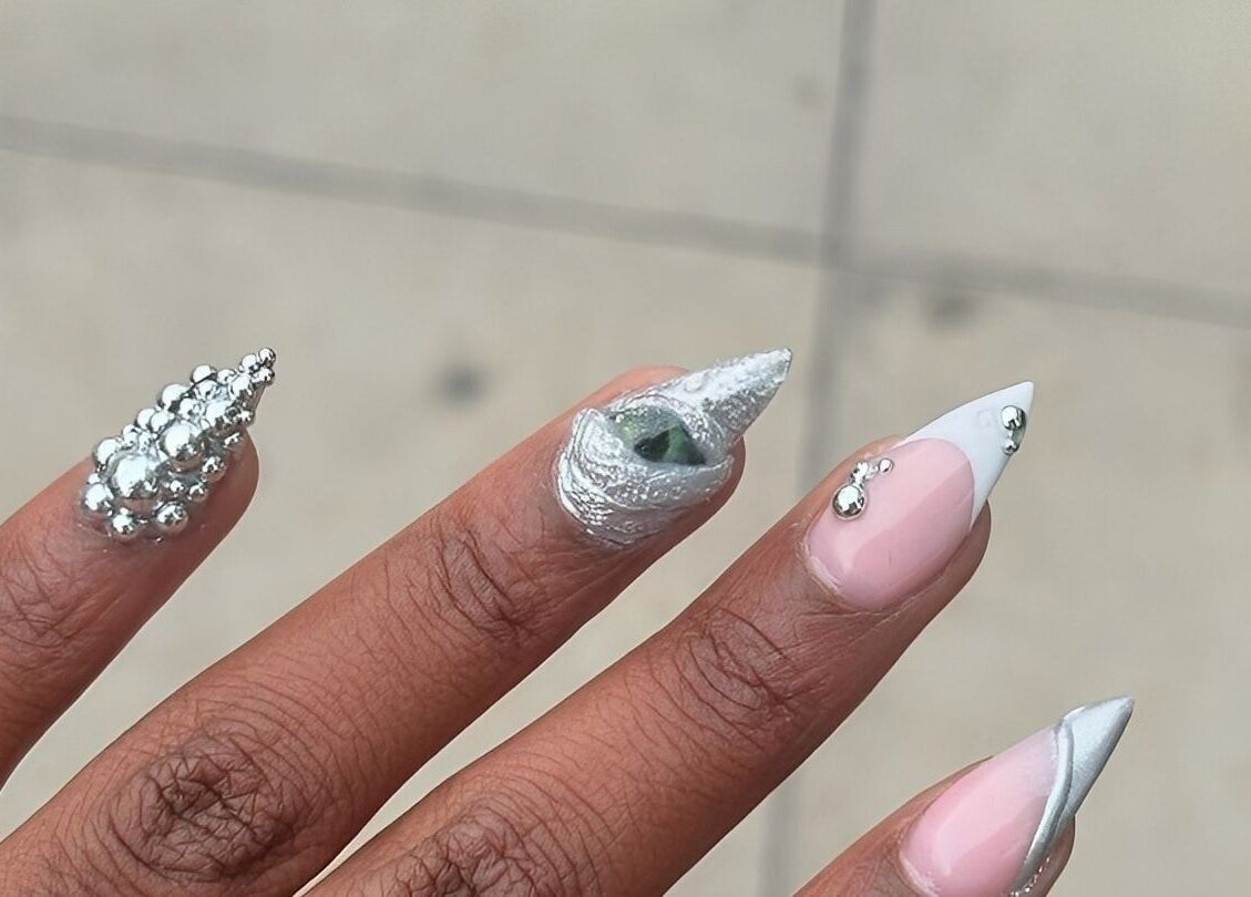 Intricate nail art design at Thee Adore Beauty Bar in London, England, GB, showcasing silver embellishments.