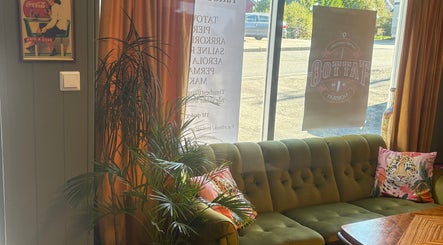Koselig lounge i Tattoo Tom Studio, Sørumsand, Akershus, NO med grønn sofa og planter.