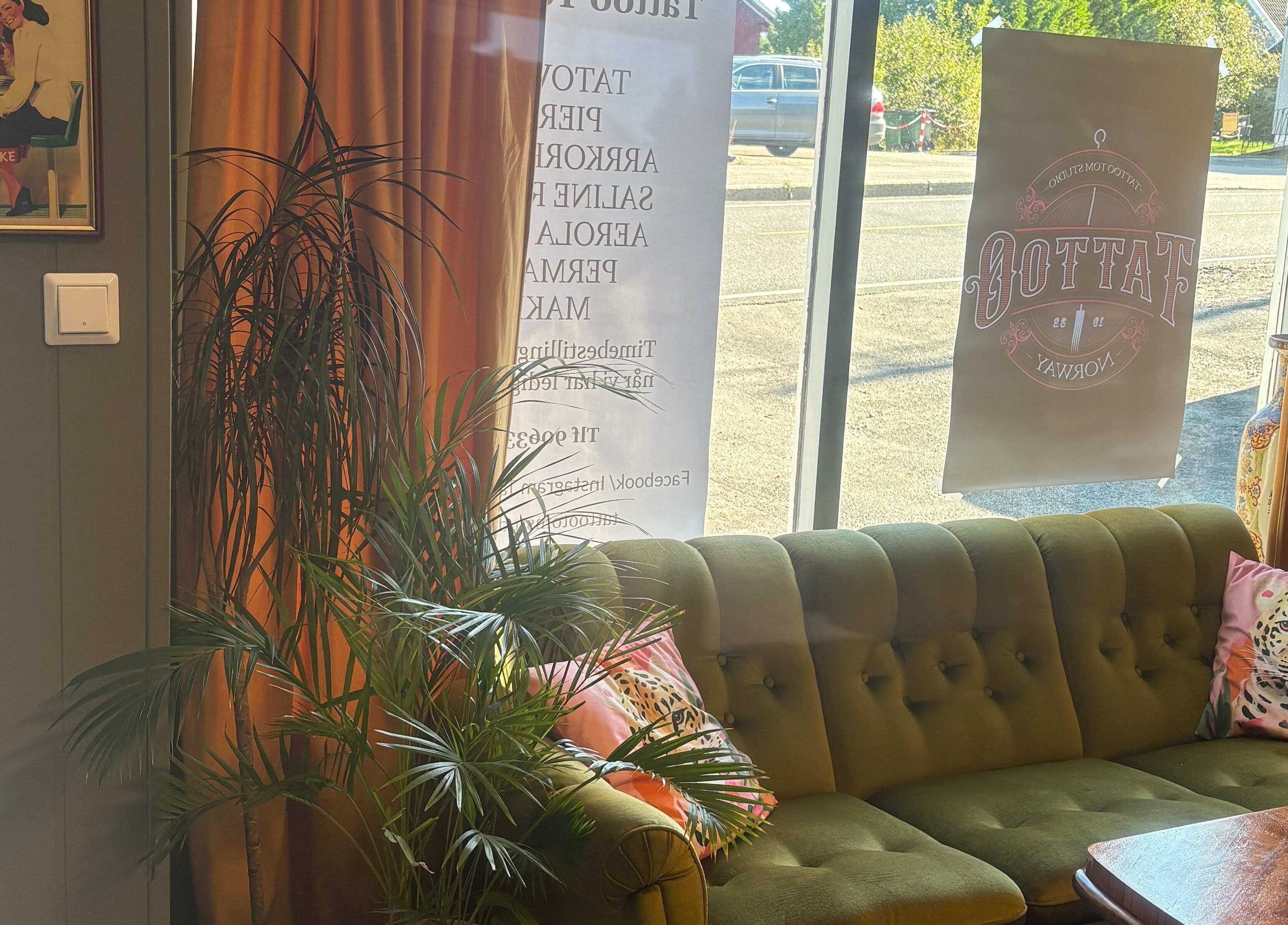 Koselig retro loungeområde hos Tattoo Tom Studio i Sørumsand, Akershus, NO med grønn sofa og vintage plakat.