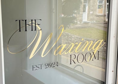 Elegant window signage of The Waxing Room in Pencoed, Wales, GB, showcasing gold lettering.