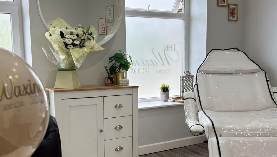 Bright, elegant interior of The Waxing Room in Pencoed, Wales, GB, with white decor and floral accents.