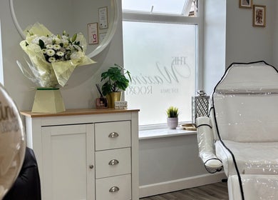 Bright, elegant interior of The Waxing Room in Pencoed, Wales, GB, with white decor and floral accents.