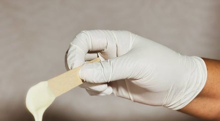 Expert waxing service at The Waxing Room, Pencoed, Wales, GB, showcasing a gloved hand holding waxing spatula.