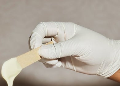 Gloved hand holding wax applicator at The Waxing Room, Pencoed, Wales, GB.