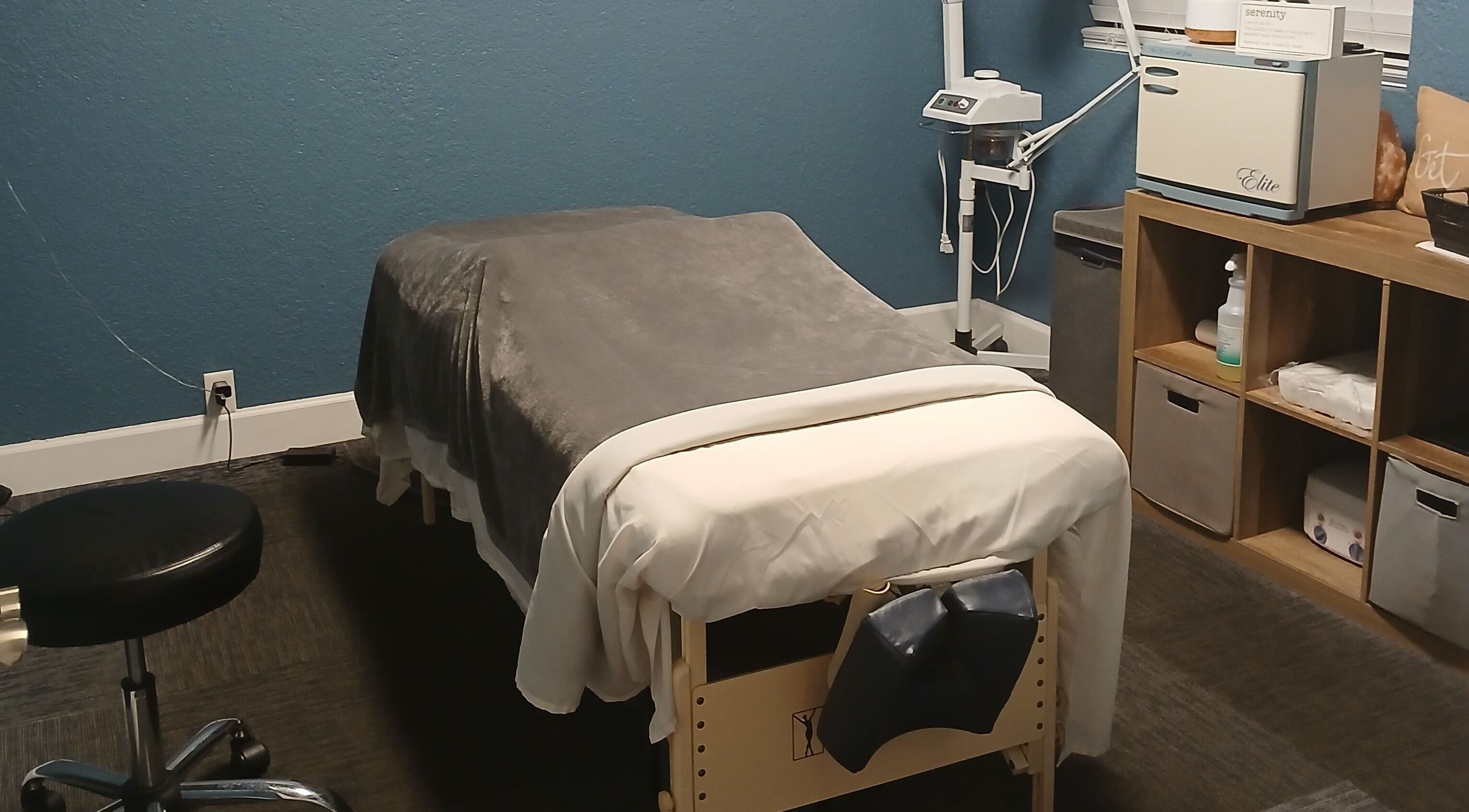 Cozy massage room at Massageology, Middleburg, Florida, US, featuring a comfortable table with a soft gray blanket.