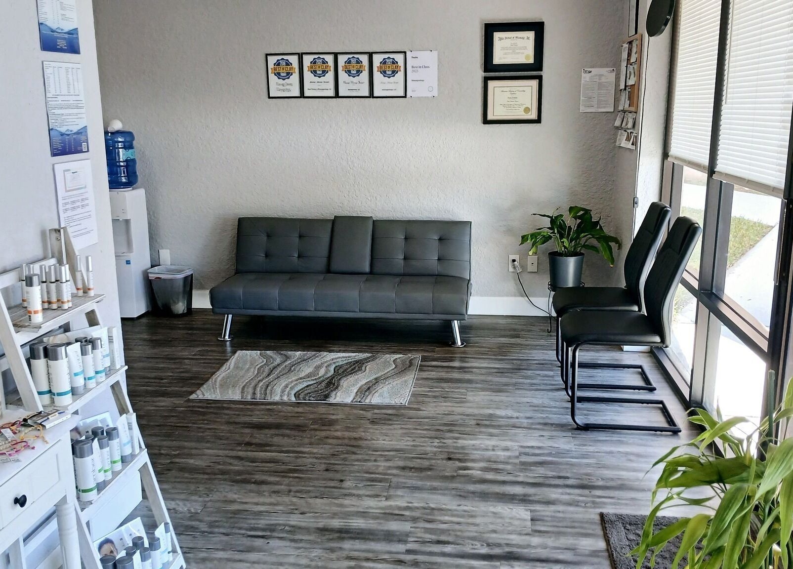 Welcoming lounge area at Massageology, Middleburg, Florida, US, featuring cozy seating and decorative plants.