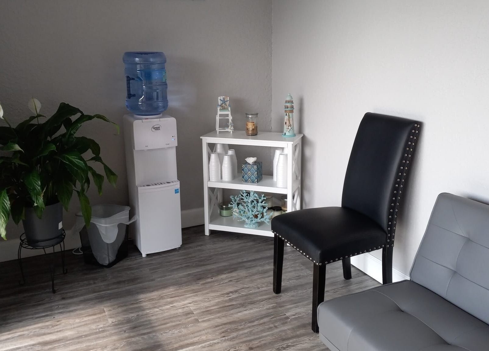 Relaxing corner at Massageology in Middleburg, Florida, US, featuring cozy seating and a calming plant display.