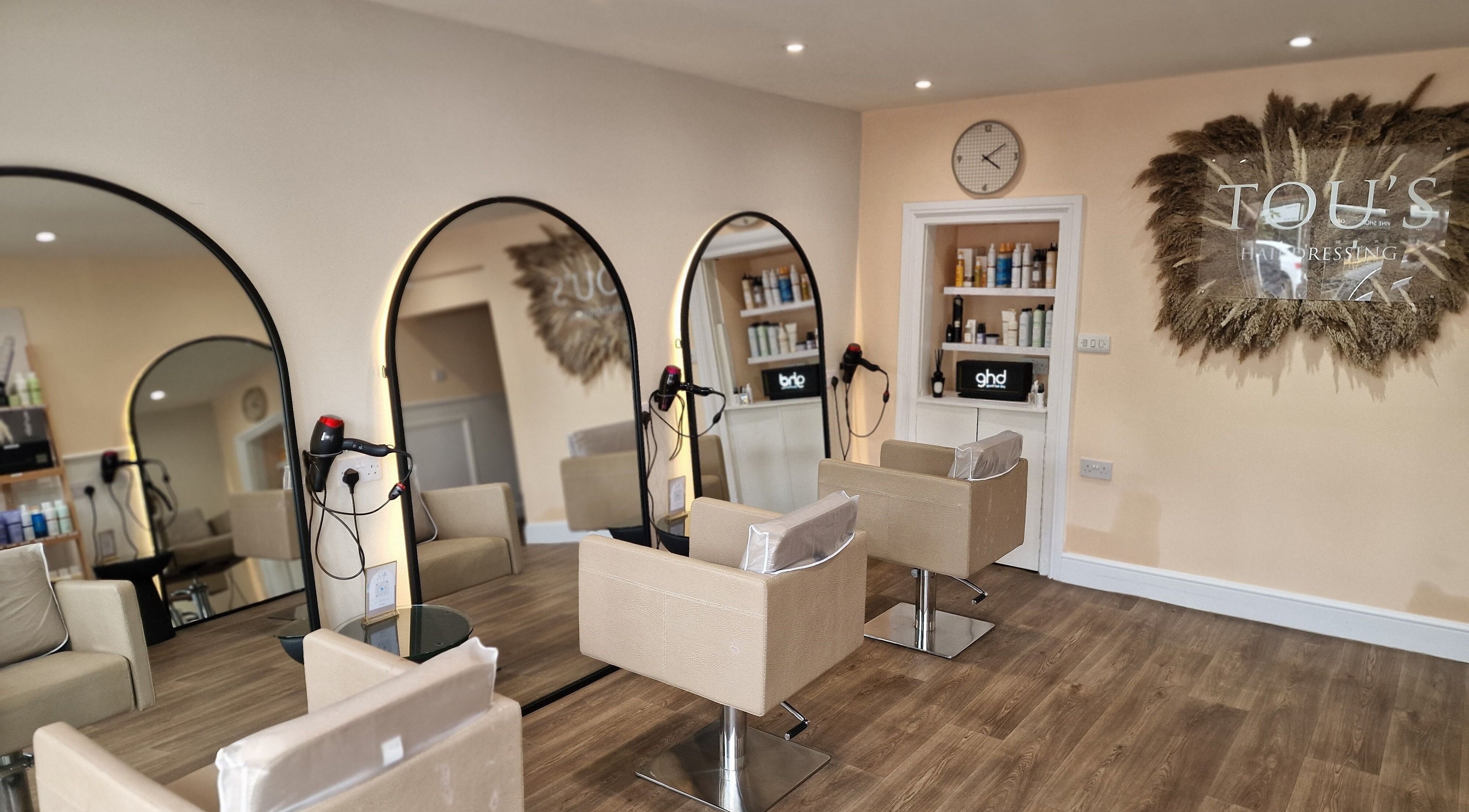Modern interior of TOU'S Hairdressing in Baldock, England, GB featuring stylish mirrors and salon chairs.