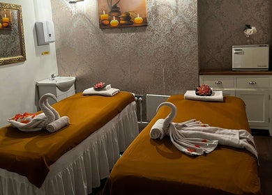 Elegant massage room at Kobkun Thai Spa, London, England, GB with two beds adorned with swan-shaped towels.