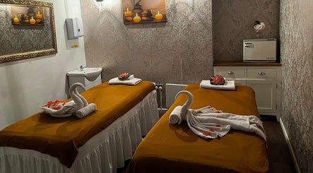 Elegant massage room at Kobkun Thai Spa, London, England, GB with two beds adorned with swan-shaped towels.