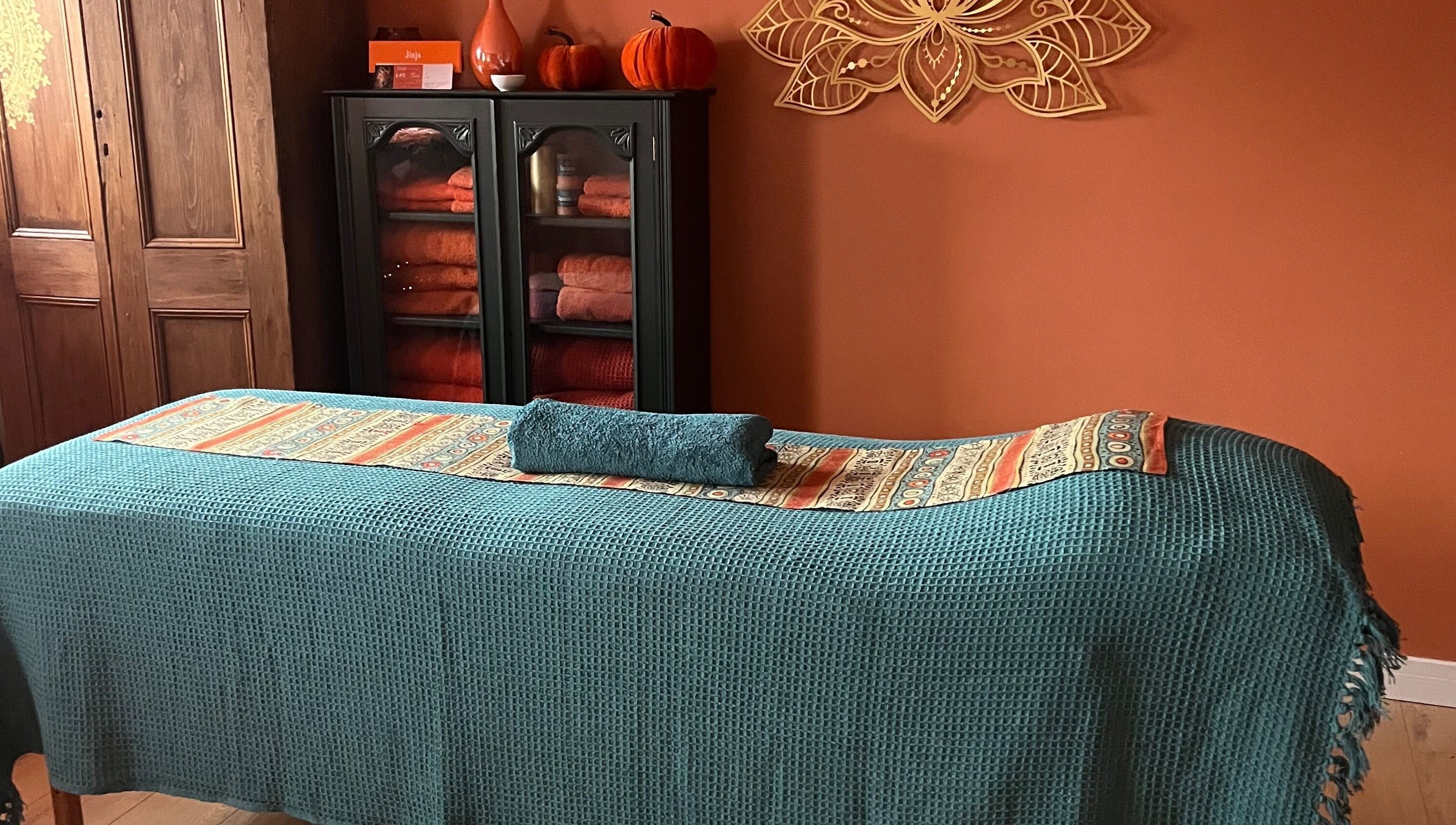 Calm therapy room at Jinja, Devizes, England, GB with teal massage table and cozy decor for relaxation.