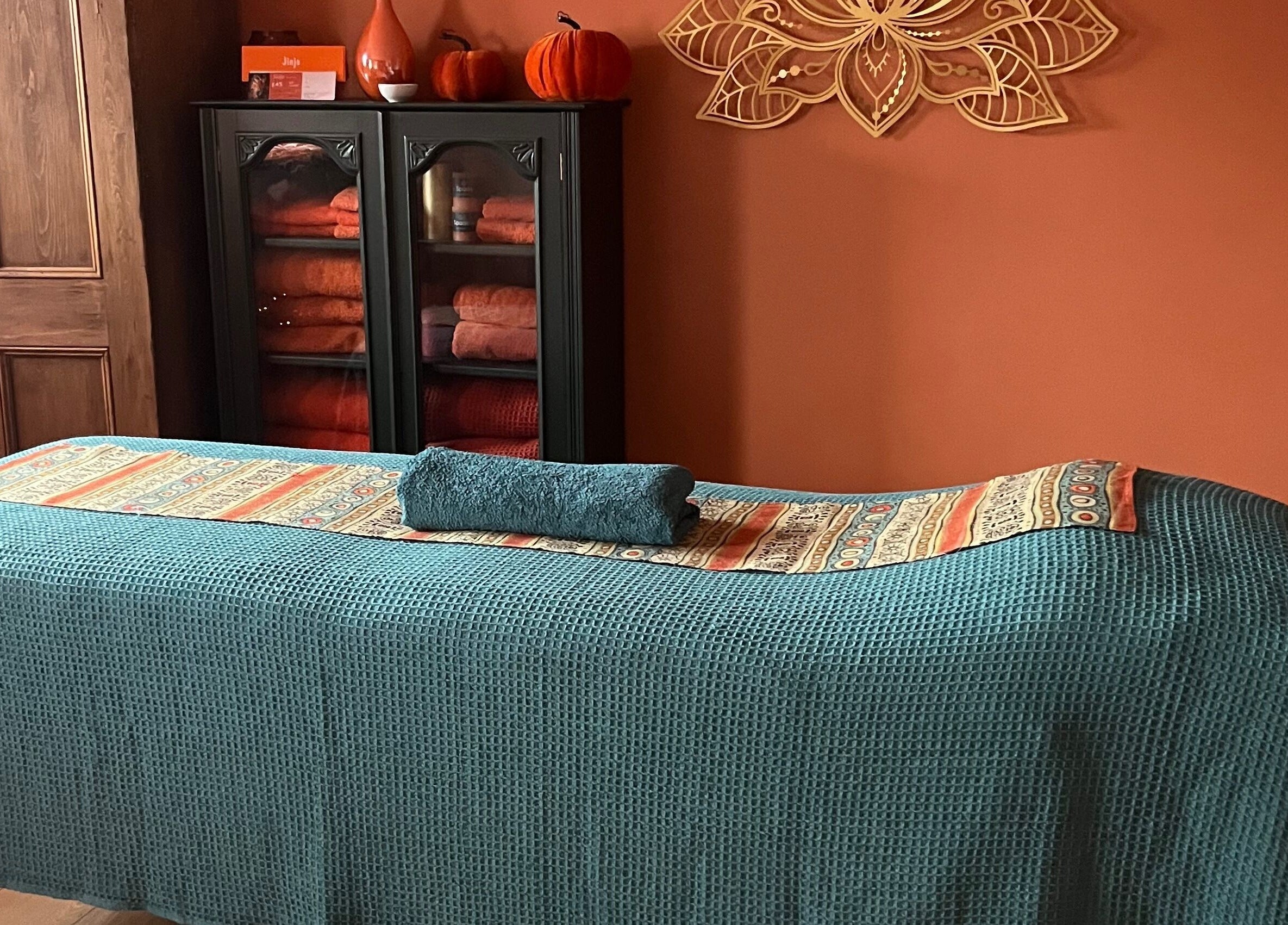 Calm therapy room at Jinja, Devizes, England, GB with teal massage table and cozy decor for relaxation.