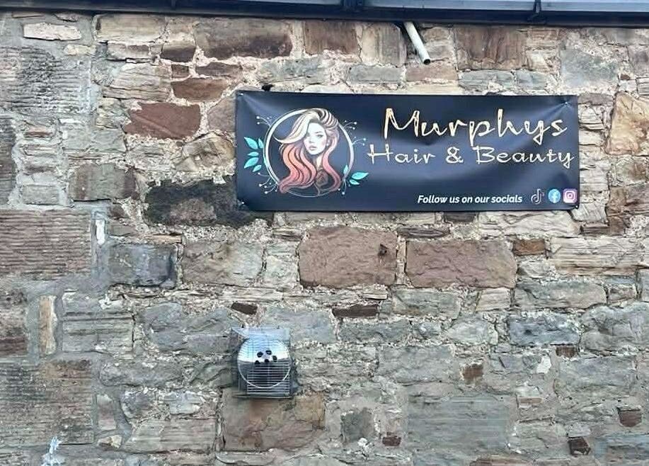 Murphys Hair & Beauty Salon Limited sign on rustic stone wall in East Calder, Scotland, GB.