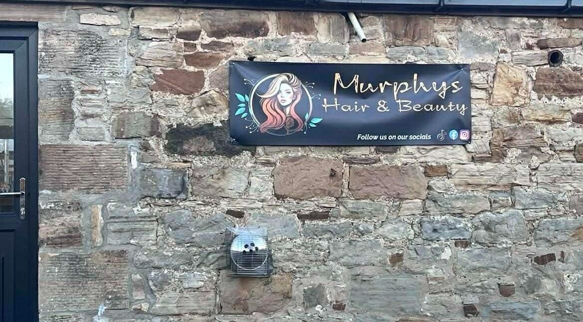 Murphys Hair & Beauty Salon Limited sign on rustic stone wall in East Calder, Scotland, GB.