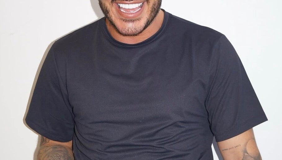 Man with tattoos on arm smiles at Dean Aesthetics, Little Lever, England, GB.
