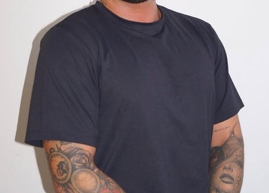 Dean Aesthetics expert with tattooed arm in Little Lever, England, GB, showcasing artistry and style.