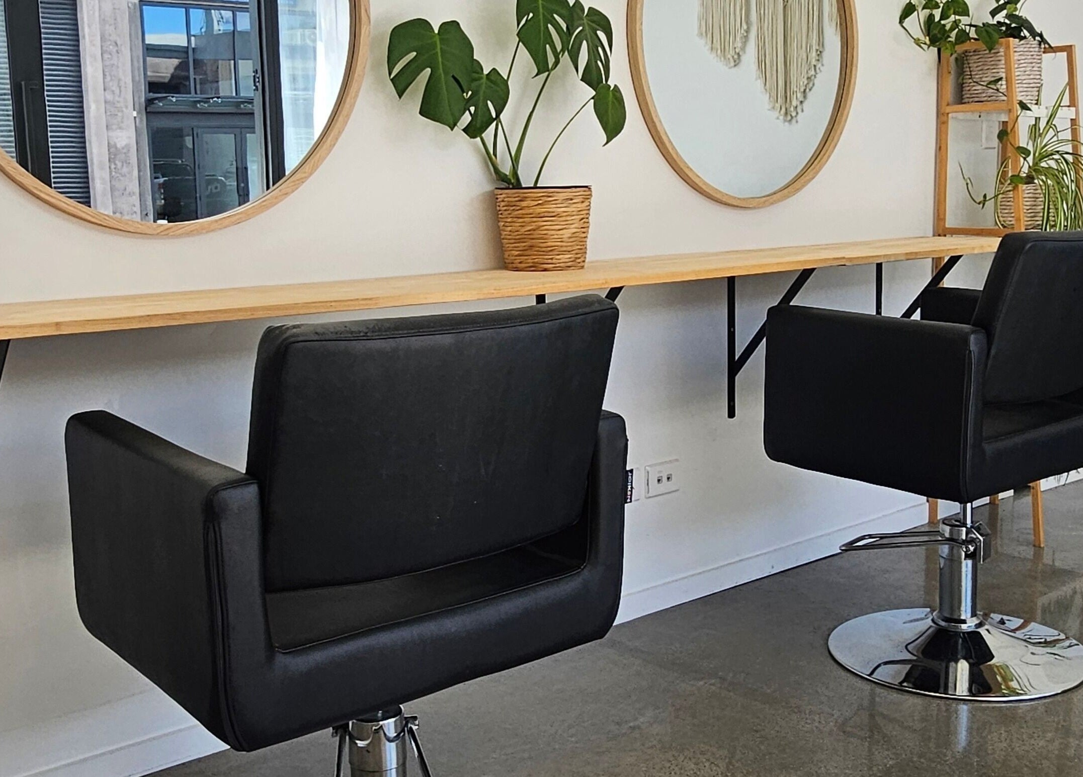 Chic hair styling chairs at Loretta's Hair Spa, Papamoa, Bay Of Plenty, NZ, set against stylish mirrors and plants.