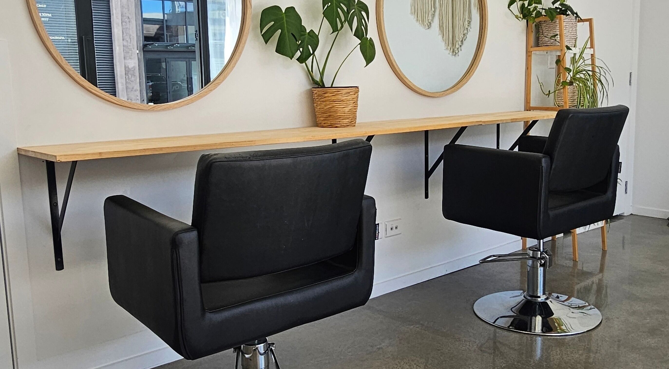 Chic hair styling chairs at Loretta's Hair Spa, Papamoa, Bay Of Plenty, NZ, set against stylish mirrors and plants.