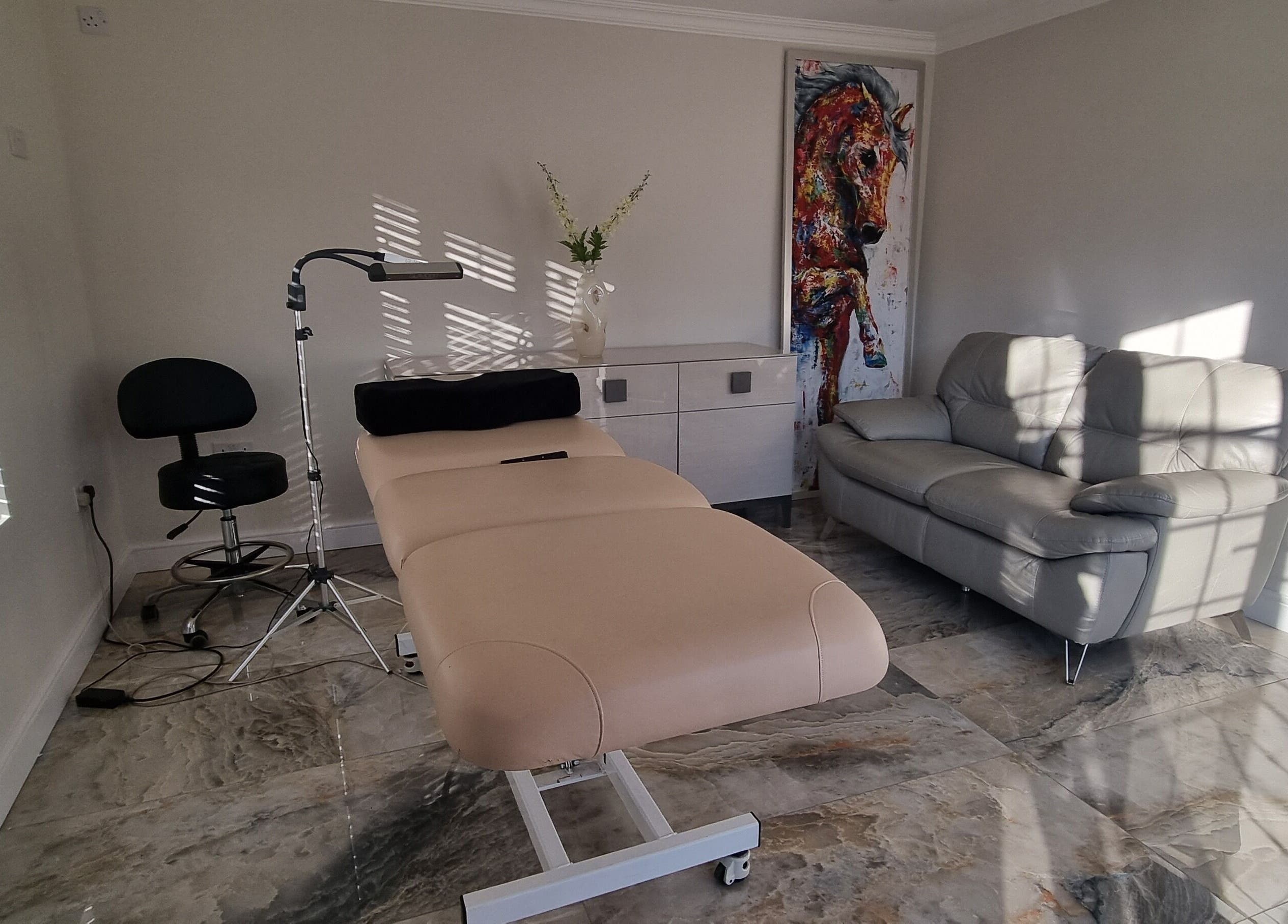 A tranquil treatment room at Inabrows, Great Baddow, England, GB with a massage table, cozy chair, and art.