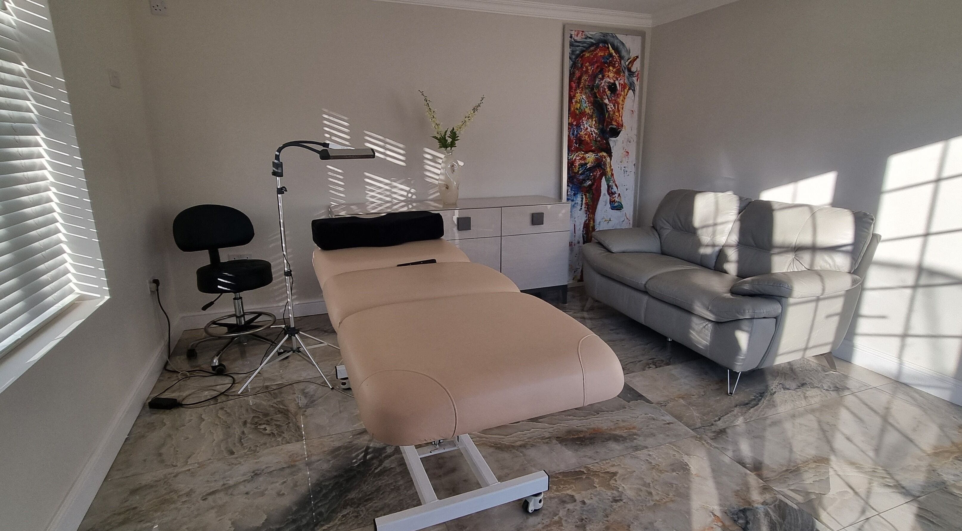 A tranquil treatment room at Inabrows, Great Baddow, England, GB with a massage table, cozy chair, and art.