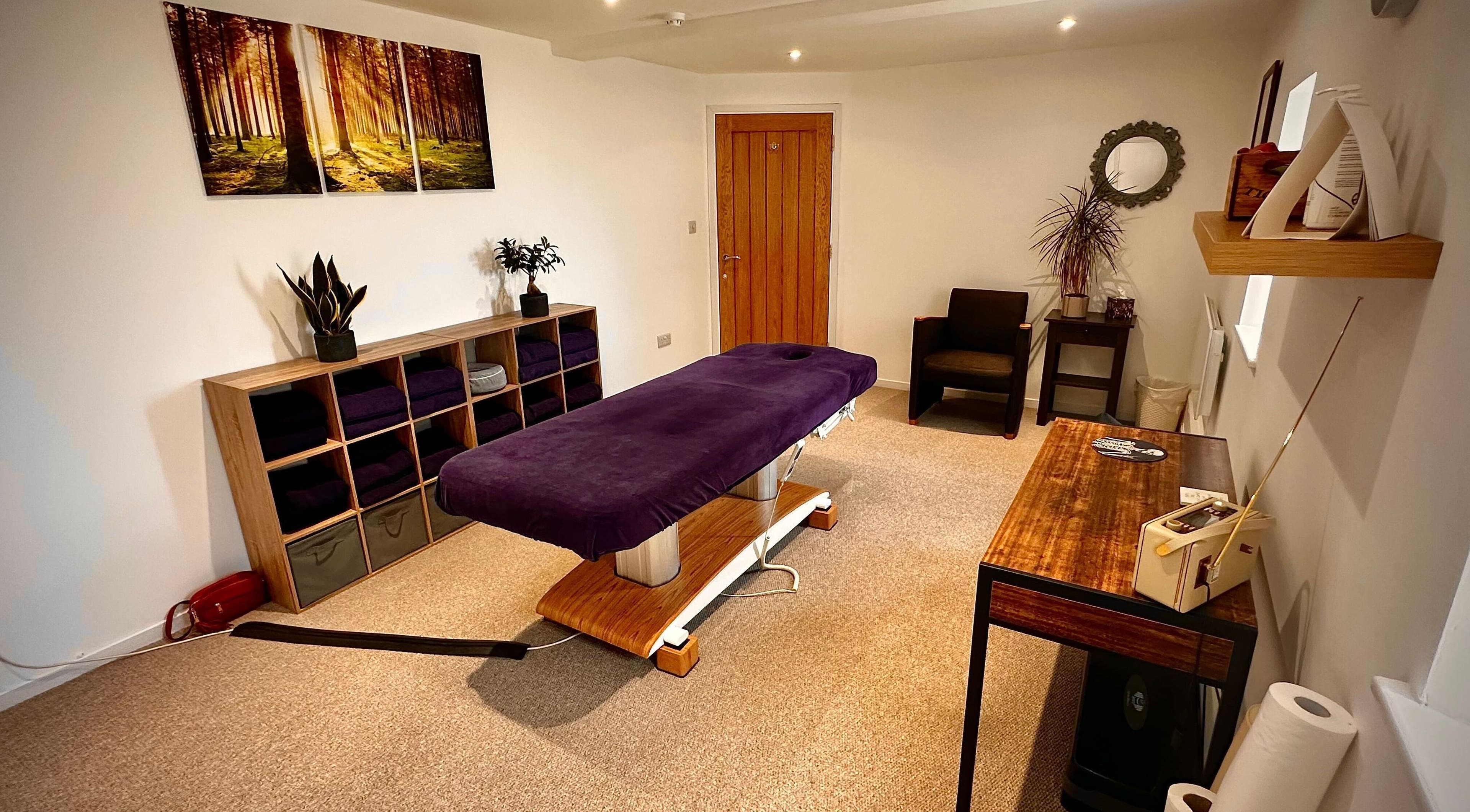 Serene treatment room at Beauty by Hand, Malmesbury, England, GB with massage table and nature decor.