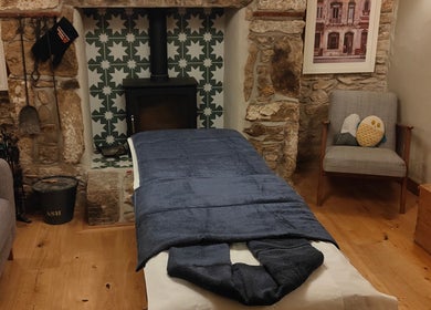 Inviting massage room at Holly Holmes Sports Massage, Falmouth, England, GB with rustic ambiance and fireplace.