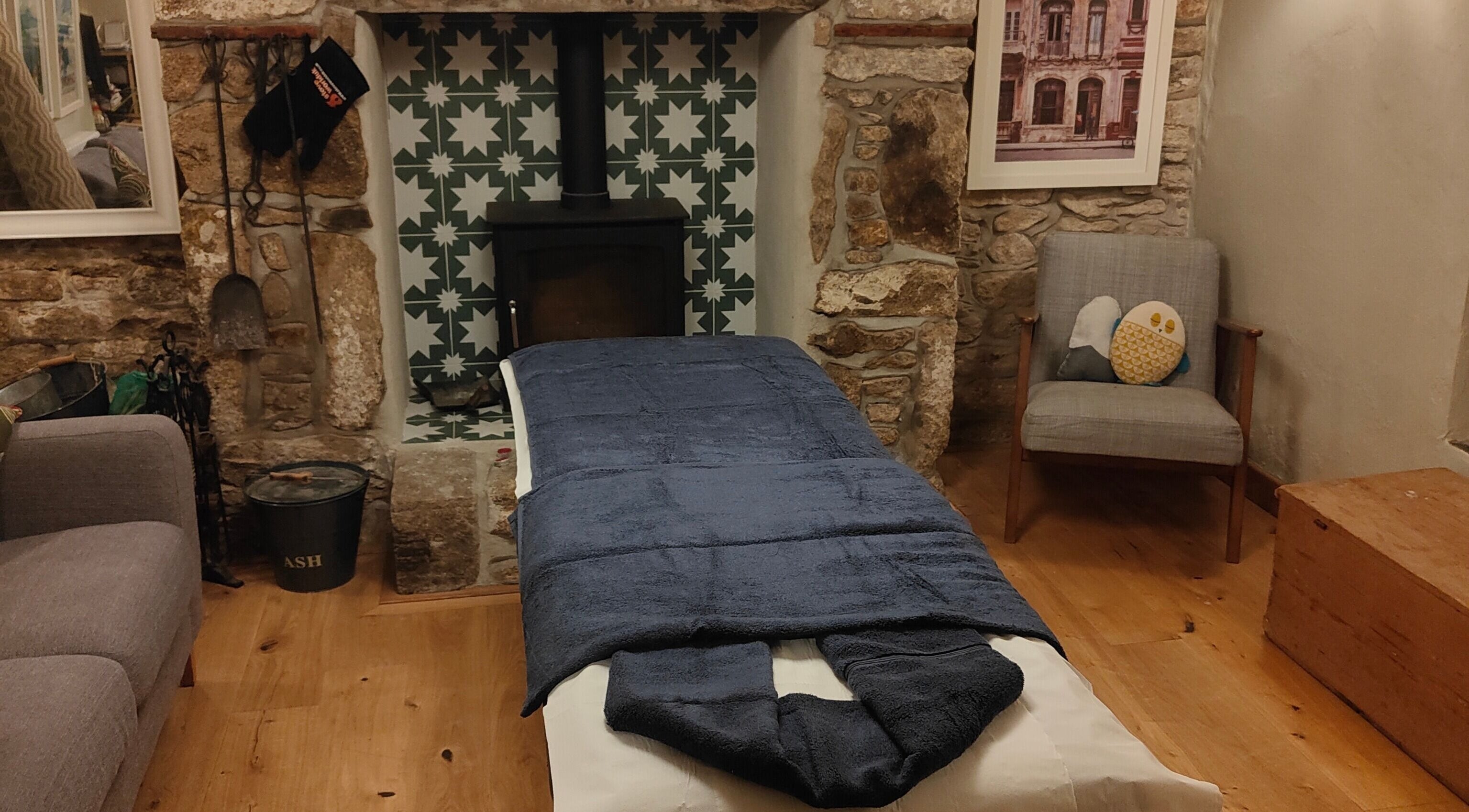 Inviting massage room at Holly Holmes Sports Massage, Falmouth, England, GB with rustic ambiance and fireplace.