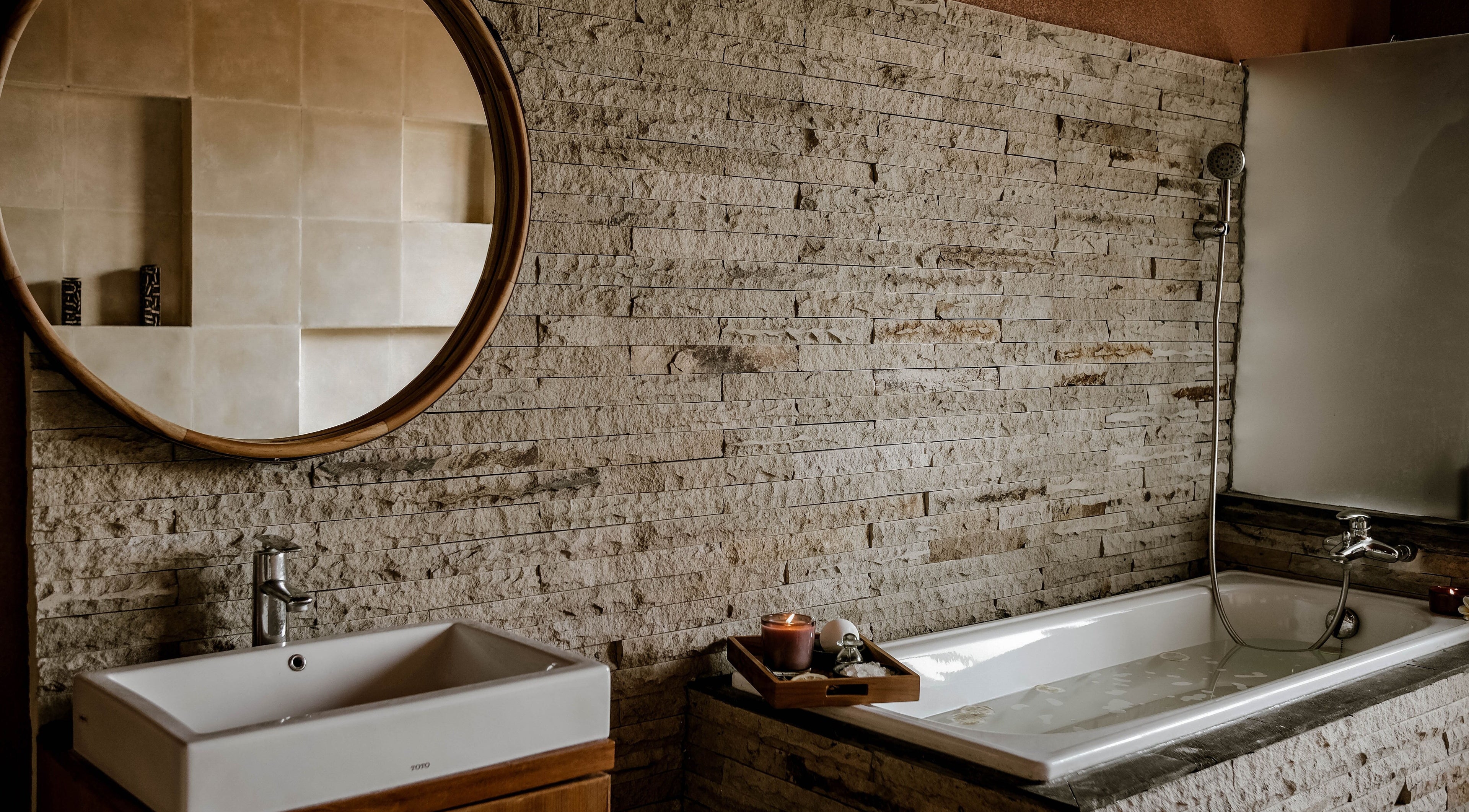 Elegant bathroom at Rituals Wellness Spa in Bali, Bali, ID, with rustic stone walls and modern fixtures.