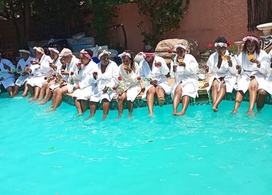 Group enjoying poolside robes at Bohl Squared Beauty Spa, Springs, Gauteng, ZA, holding roses and drinks.