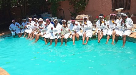 Group enjoying poolside robes at Bohl Squared Beauty Spa, Springs, Gauteng, ZA, holding roses and drinks.