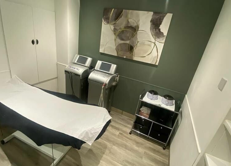 Calm treatment room at Harmony in Brentwood, England, GB, featuring modern medical equipment and a massage table.