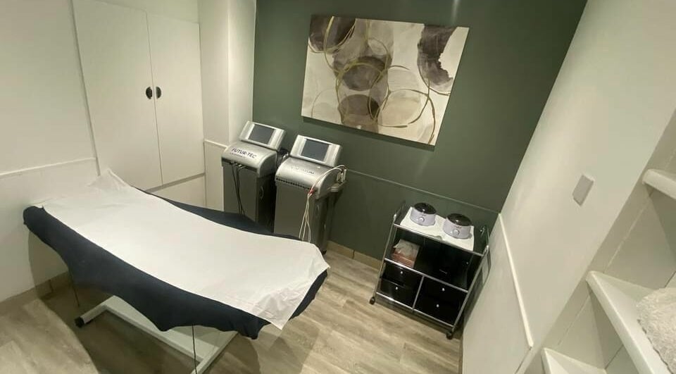 Calm treatment room at Harmony in Brentwood, England, GB, featuring modern medical equipment and a massage table.