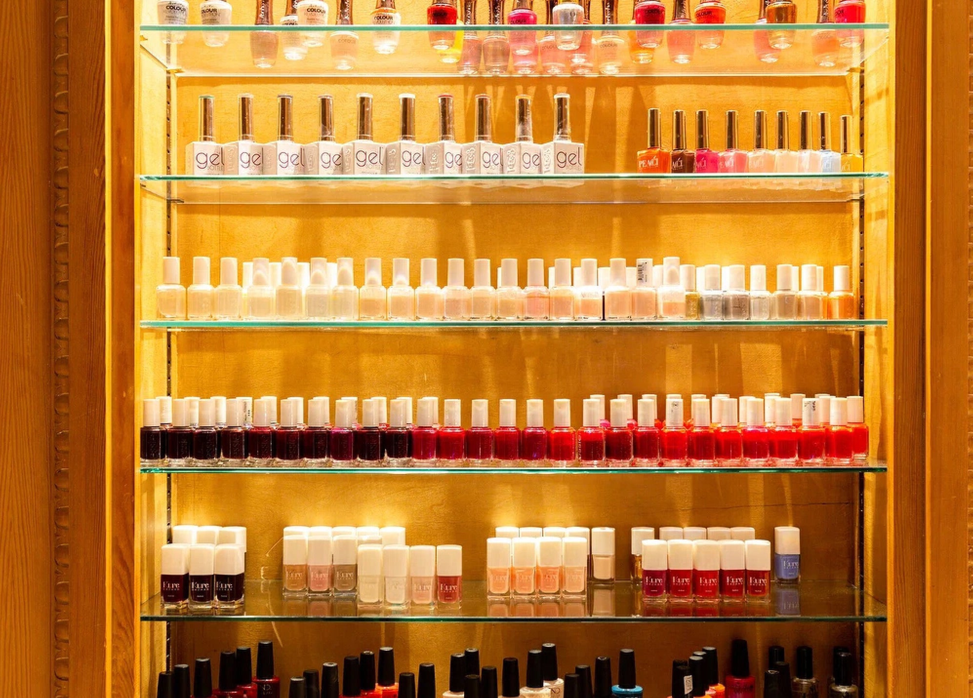 Vibrant nail polish display at The Nail Station, London, England, GB. Rows of colorful bottles on sleek shelves.