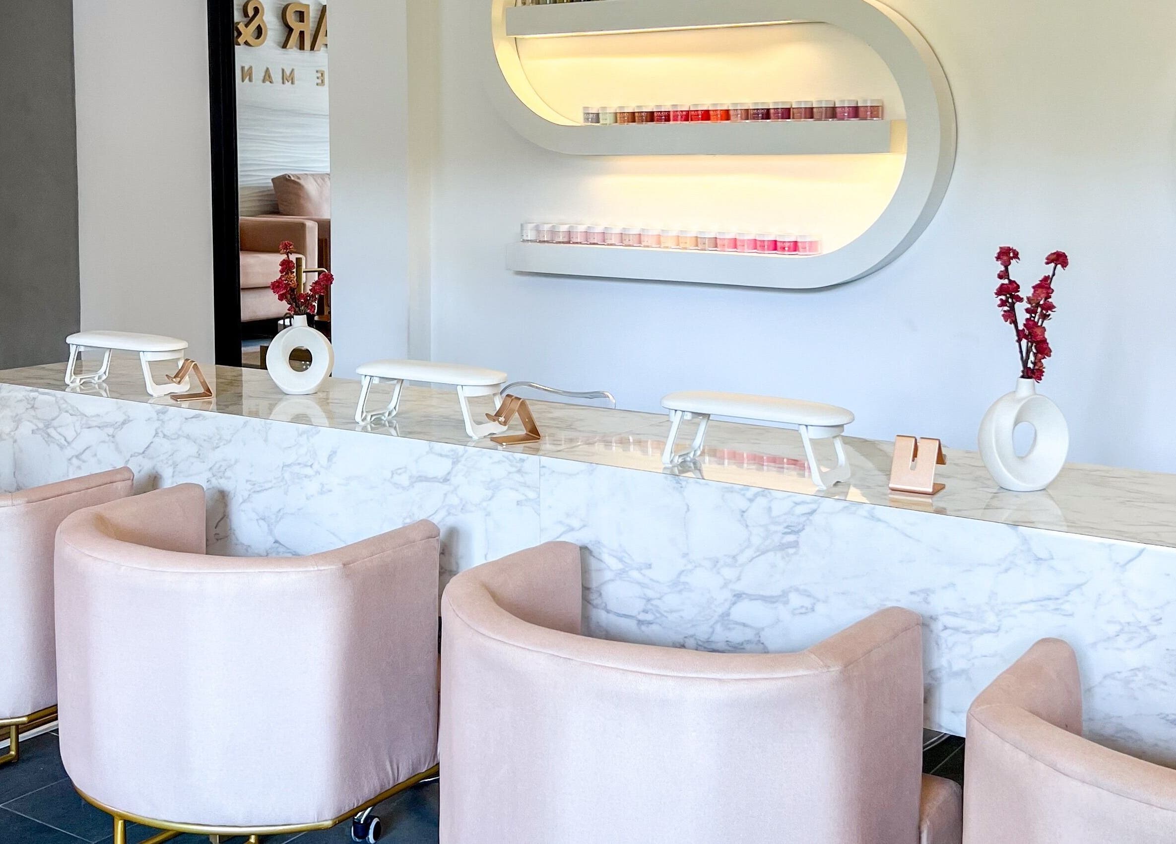 Área de manicura elegante en Glow Haus GT, Ciudad De Guatemala, Guatemala, GT, con sillas rosadas y encimera de mármol.