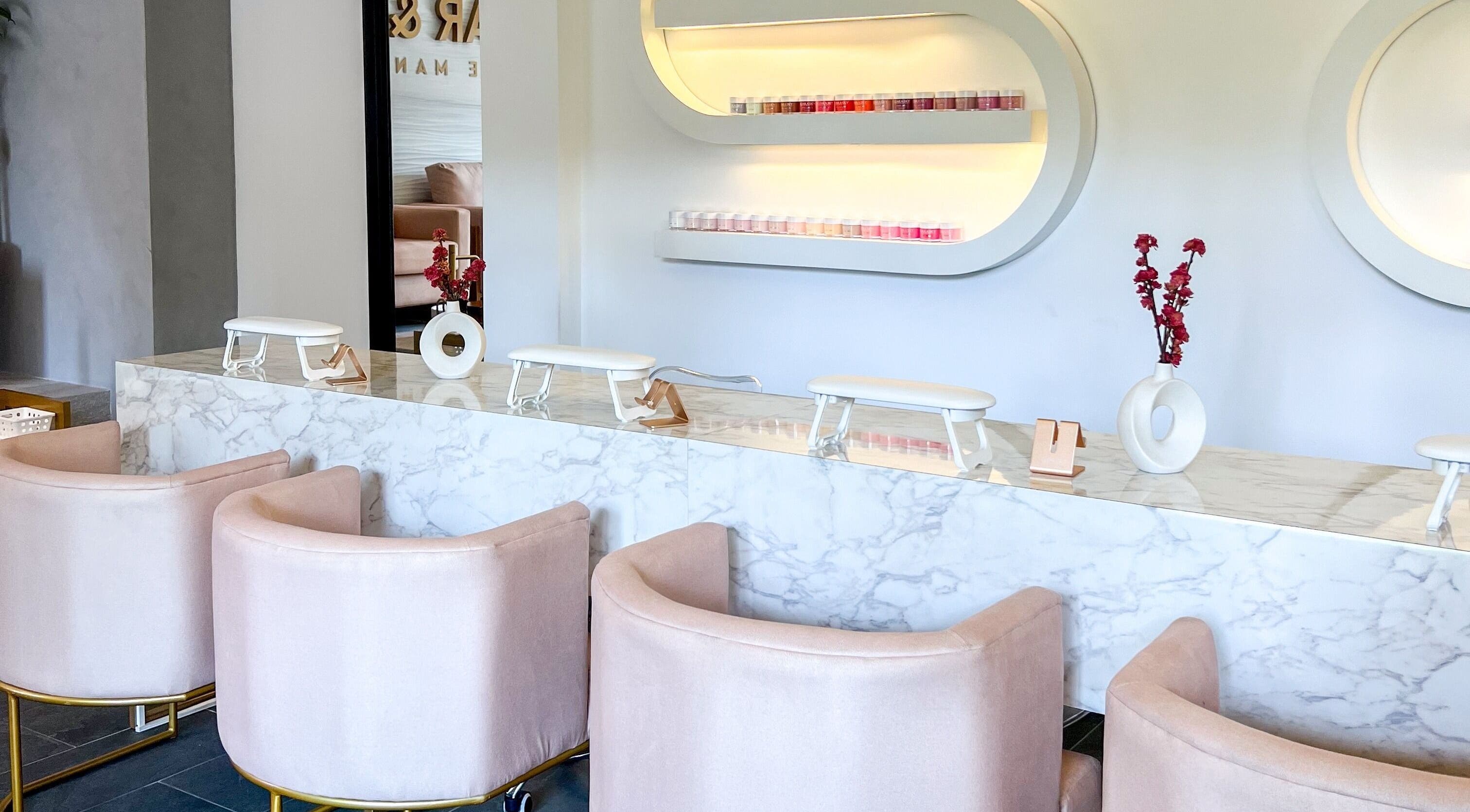 Área de manicura elegante en Glow Haus GT, Ciudad De Guatemala, Guatemala, GT, con sillas rosadas y encimera de mármol.