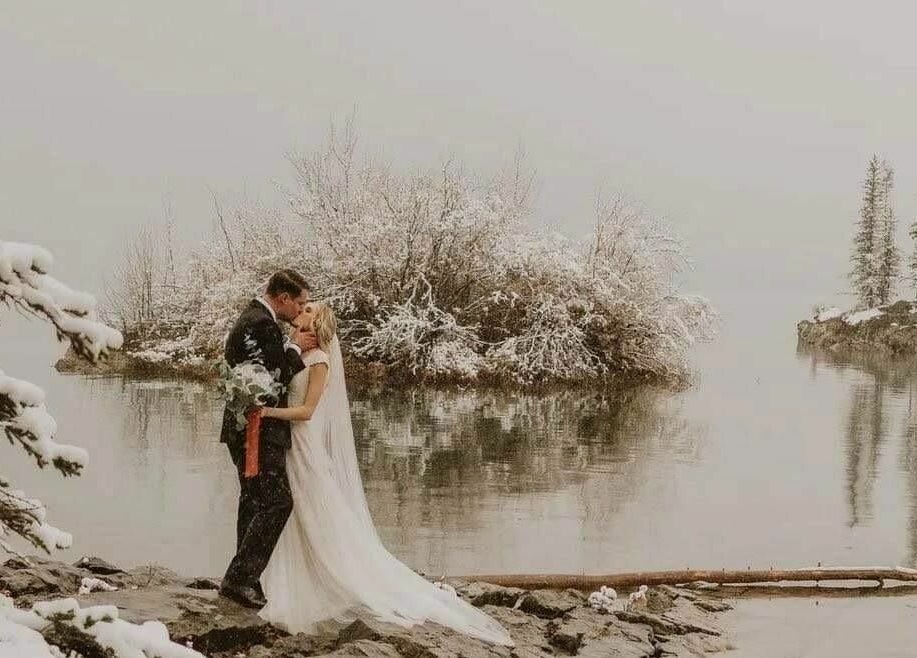 Winter wedding at scenic Banff, Alberta with Botega Salon and Gallery styling. Couples embrace by snowy lake.